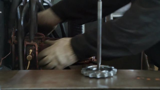 The working specialist prepares and adjusts the equipment for hardening and heat treatment of metal parts before starting work, close-up, metalworking