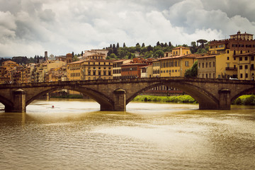 Panoramic view of the city of Florence. Storm clouds cover the sky. A small rowing boat circulates...