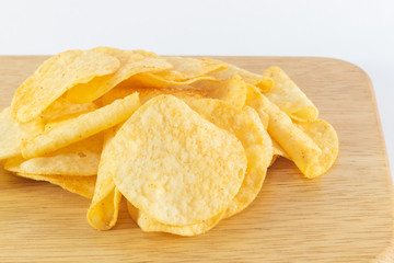 Close up potato chips on wooden board.