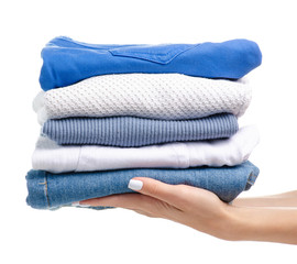 Stack of clothing jeans sweaters in hand on a white background isolation