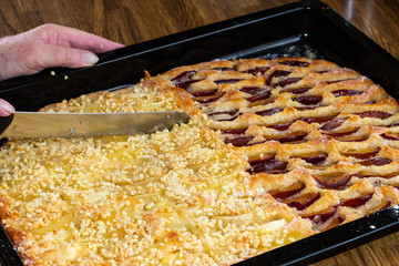 Obstkuchen mit Hefeteig auf Backblech mit Pflaumen und Äpfel im Backofen frisch gebacken.