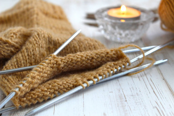 Knitting a sock, brown. The candle is burning. Rest, autumn mood. The concept of retirement age and quiet old age.
