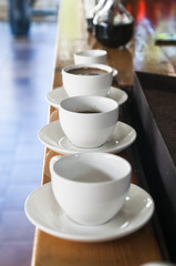 row of white cups with coffee with