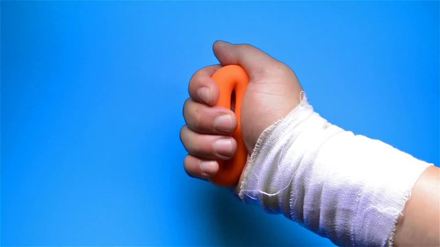 a hurt hand doing rehabilitation exercises by squeezing a hand grip ring