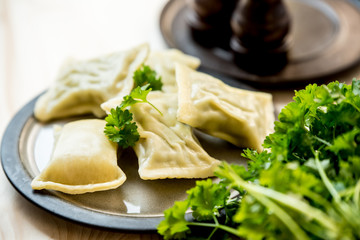 maultaschen, German, traditional dumplings on plate, next to fresh parsley, salt shaker and pepper pot