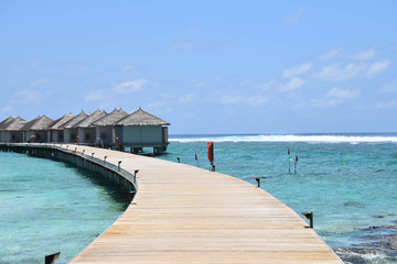 Overwater Bungalows and villas, over crystal clear blue ocean, on a tropical island in the Maldives