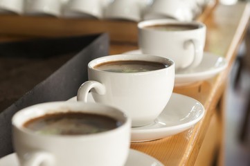 row of white cups with coffee with