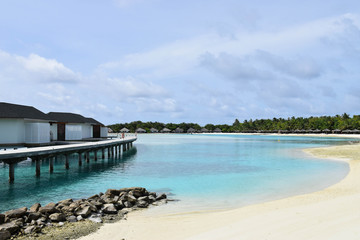 Overwater Bungalows and villas, over crystal clear blue ocean, on a tropical island in the Maldives