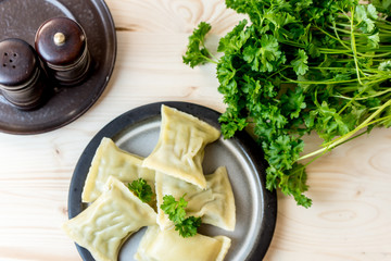 maultaschen, German, traditional dumplings on a plate, next to fresh parsley, salt shaker and pepper pot