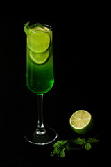green mojito cocktail in the glass and lime on the dark background