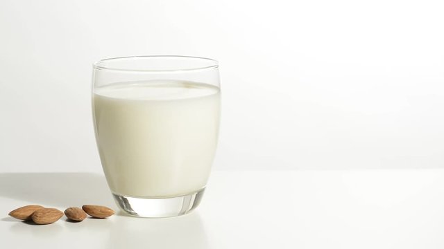 Vaso de leche y almendras en la mesa blanca