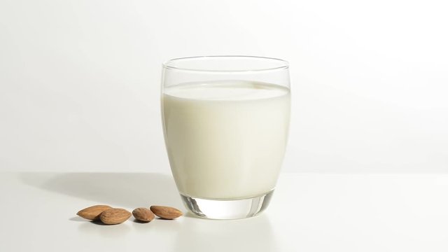 Vaso de leche y almendras en la mesa blanca