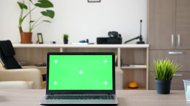 Laptop computer with green screen mock up on a desk in the middle of living room. Dolly slider 4K footage