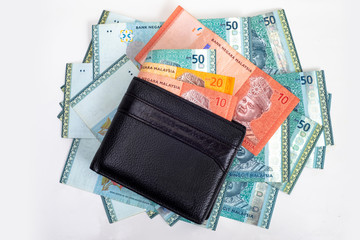 black PU leather men’s wallet on the pile of Malaysian Ringgits, isolated on white background