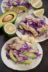 Mexican tacos with red cabbage, grilled chicken fillet, avocado, lime and cheese topping, selective focus