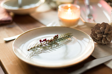 christmas, holidays and table setting concept - plate decorated with fir branch for festive dinner at home