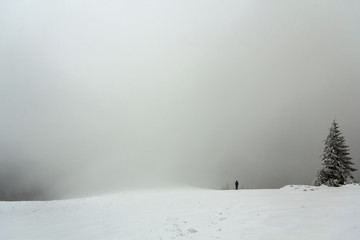 Naklejka premium Far away lonely figure of a man standing outdoors in winter