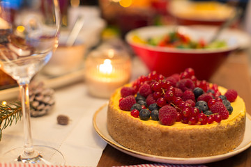 christmas dinner and eating concept - close up of berry cake and other food on table at home