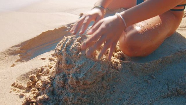 Attractive young woman building a horrible sandcastle on the beach