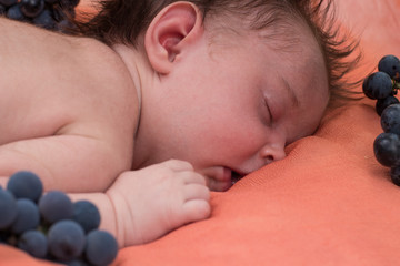 a newborn sleeps on a coverlet