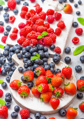 Obraz premium Fresh raw organic berries on vintage chopping boards on kitchen table background. Top view. Strawberry, Raspberry, Blueberry and Mint leaf