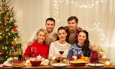 holidays and celebration concept - happy friends having christmas dinner at home