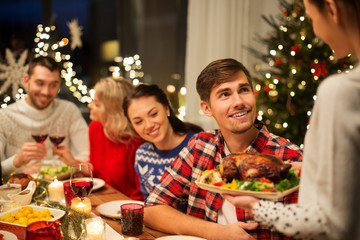 Obraz na płótnie Canvas holidays and celebration concept - happy friends having christmas dinner at home