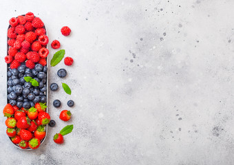 Fresh raw organic berries in in stainless steel tray on kitchen table background. Space for text. Top view. Strawberry, Raspberry, Blueberry and Mint leaf