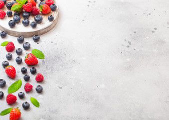 Fresh raw organic berries on round vintage board background. Space for text. Top view. Strawberry, Raspberry, Blueberry and Mint leaf