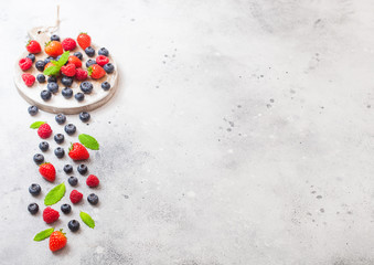 Fresh raw organic berries on round vintage board background. Space for text. Top view. Strawberry, Raspberry, Blueberry and Mint leaf