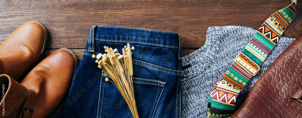 Wall mural Women's clothing and accessories on a wooden background, red shoes, bag, jeans and sweater, hipster style, long banner