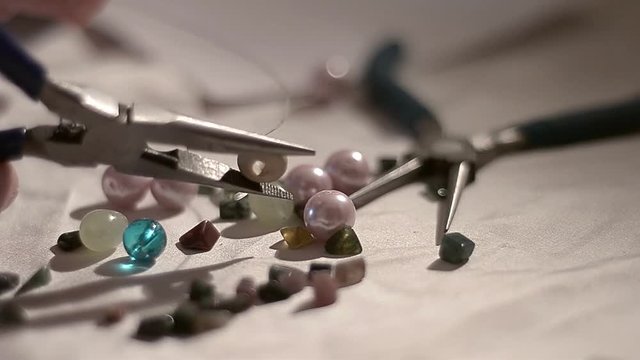 Making jewellery by threading a bead onto silver wire with jewellery pliers