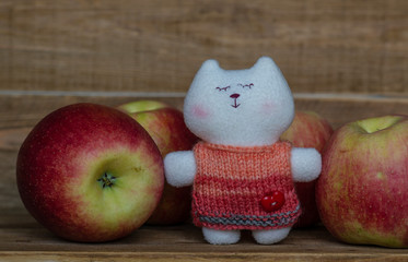 Closeup of red big  apples and a small toy cute cat on wooden table. small world. toys and vitamins