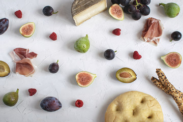 Flat kay italian wine appetizer Fig Grape Plum Cheese Focaccia Grissini Raspberry White background Copy space