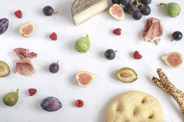 Flat kay italian wine appetizer Fig Grape Plum Cheese Focaccia Grissini Raspberry White background Copy space Toned image