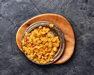 Fototapeta premium Yellow raisins on black concrete background. Top view of dried grapes.