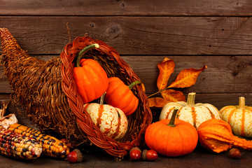 Thanksgiving cornucopia filled with pumpkins against a rustic wooden background