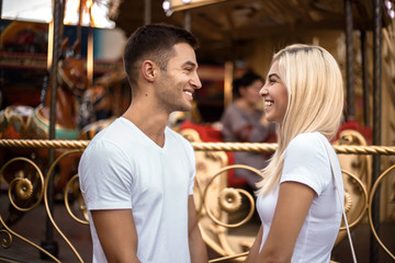 Laughing loving couple walking outdoors in the amusement park posing.