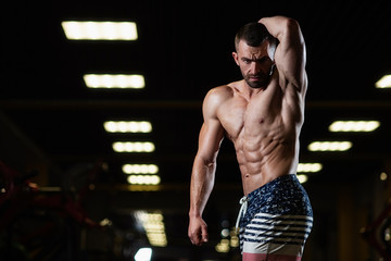Strong fitness man demonstrates abdominal muscles in the gym. The concept of a healthy lifestyle