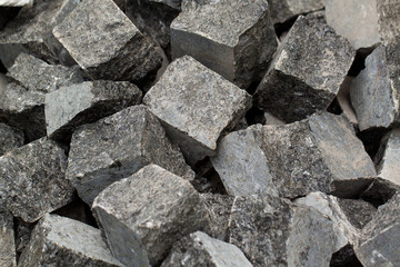 stones of dark gray marble or granite lie in a pile, prepared for pavers
