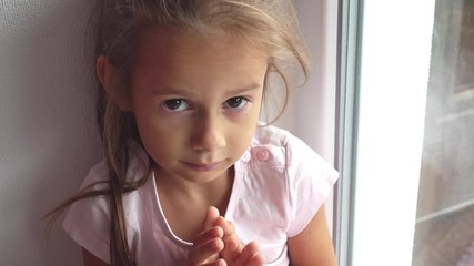 Portrait of a small sad girl by the window. Sad child looks out the window, video 4k.
- Powered by Adobe