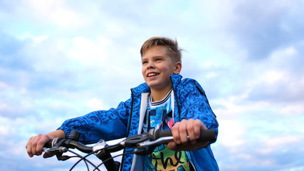 Obraz premium Teenager riding a bike, doing sports in the fresh air. Travel and active entertainment. Moments of happy childhood