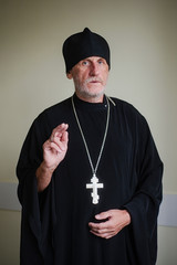 Portrait of an elderly priest with gray hair in black clothes