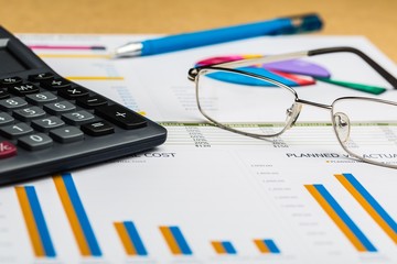 Pen, Eyeglasses and Calculator on Business Graphs and Charts