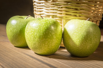 Apples next to basket.