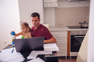 businessman working with computer while looking after his daughter..
