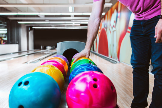 Player choosing bowling ball from rack of balls at a bowling alley