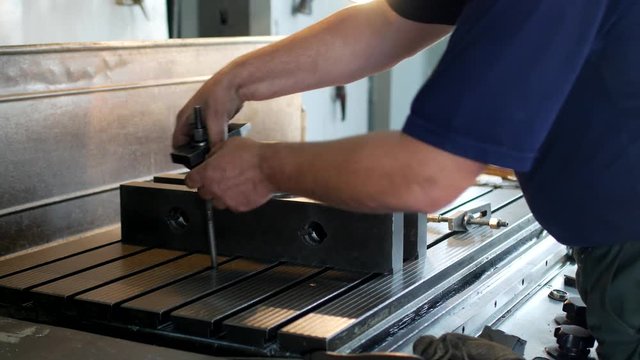 Male specialist borer fixes a metal pulley on a reaming machine, small business, close-up