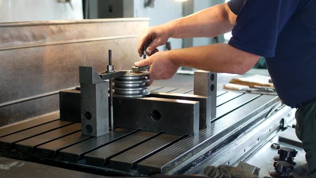 Male specialist borer fixes a metal pulley on a reaming machine, small business, block