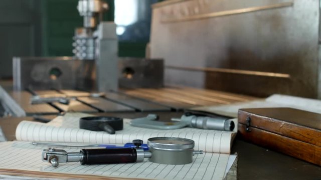 A private workshop for working with metal parts, in the background a drilling machine drills a hole in the pulley, on the table lie measuring instruments, manufactory